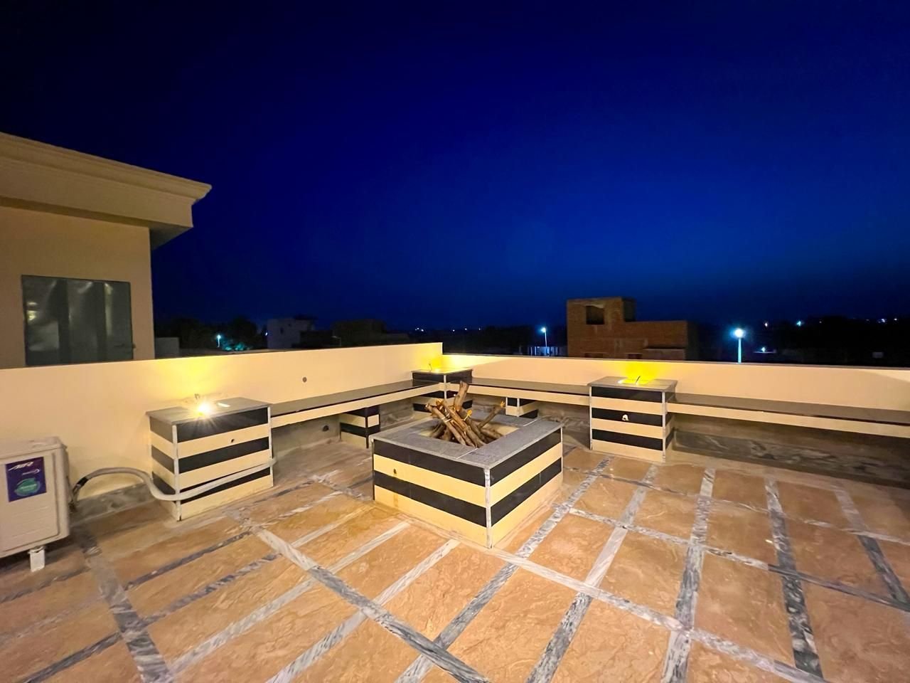 Rooftop BBQ area with fire pit at night